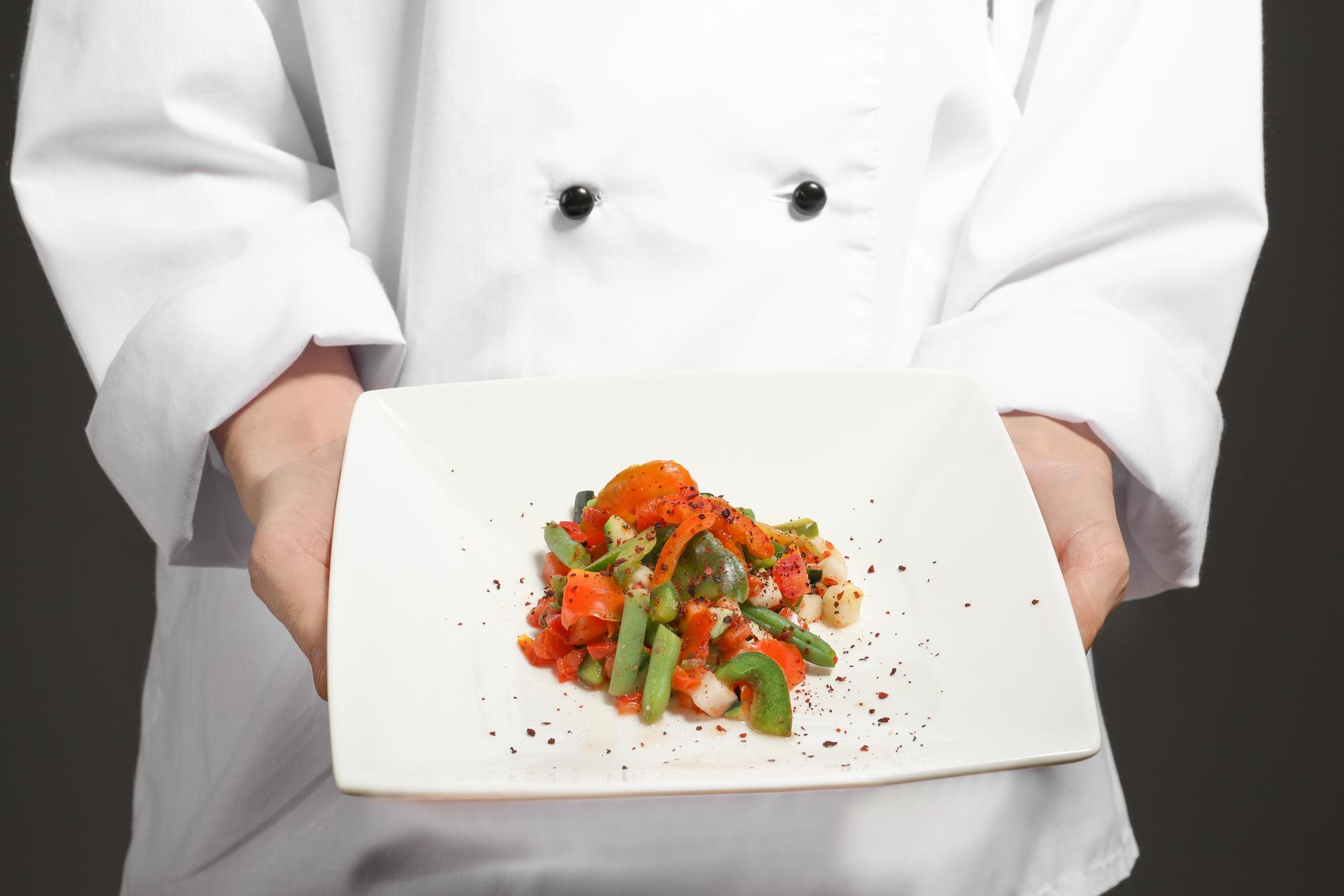 Chef che prepara una composizione di piatti su banco in cucina